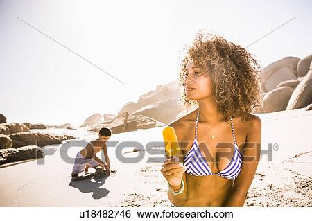 Young woman eating ice lolly on beach, Cape Town, South Africa View Large Photo Image Stock Photograph - Young woman eating ice lolly on beach, Cape Town, South Africa. Fotosearch