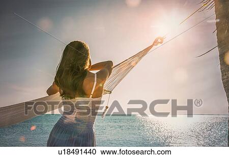Young woman leaning against hammock watching sunset on Miami Beach, Florida, USA View Large Photo Image Stock Image - Young woman leaning against hammock watching sunset on Miami Beach, Florida, USA. Fotosearch