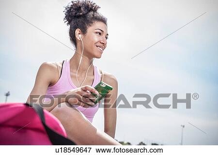 Stock Photo - Young woman training, listening to earphones. Fotosearch