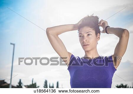 Young woman training, tying up hair at sport facility View Large Photo Image Stock Photograph - Young woman training, tying up hair at sport facility. Fotosearch