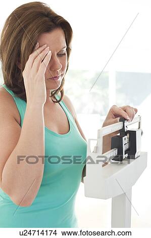 Woman weighing herself View Large Photo Image Picture - Woman weighing herself. Fotosearch
