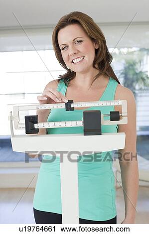 Stock Image - Woman weighing herself. Fotosearch