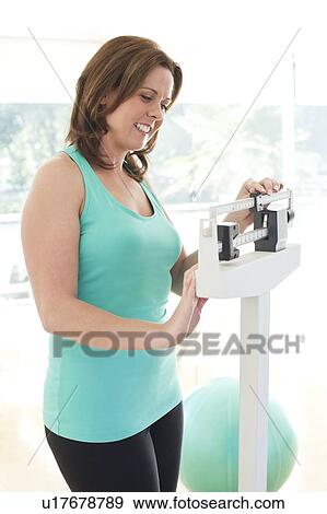 Stock Photo - Woman weighing herself. Fotosearch