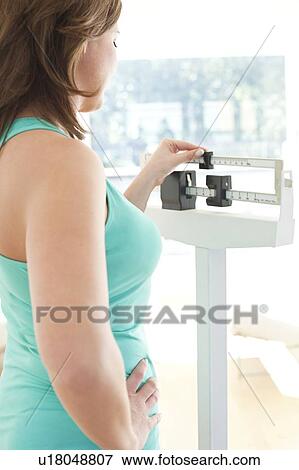 Stock Photo - Woman weighing herself. Fotosearch