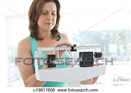 Stock Photograph - Woman weighing herself. Fotosearch