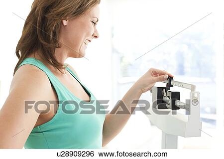 Woman weighing herself View Large Photo Image Stock Photograph - Woman weighing herself. Fotosearch