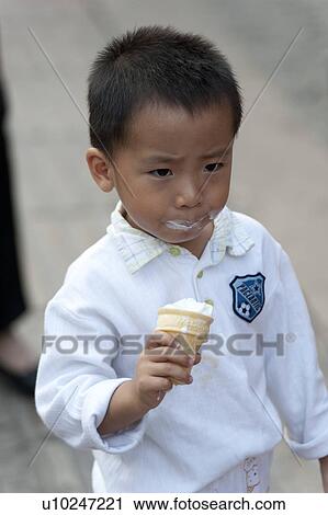 Stock Image - Boy licking an ice cream, Binhai, Tianjin, China. Fotosearch