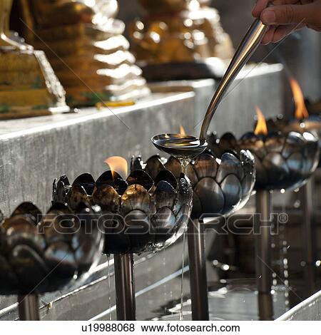 Close-up of a person's hand pouring oil into an oil lamp at Wat Phrathat Doi Suthep, Chiang Mai, Thailand View Large Photo Image Stock Photo - Close-up of a person's hand pouring oil into an oil lamp at Wat Phrathat Doi Suthep, Chiang Mai, Thailand. Fotosearch