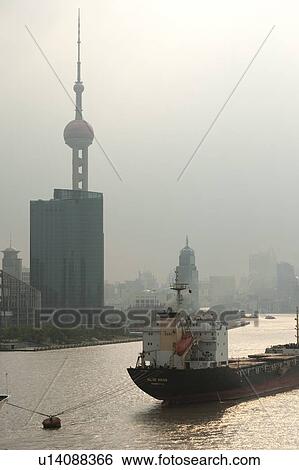 Stock Photograph - Container ship in the Huangpu River with the Oriental Pearl Tower in the background, Pudong, Shanghai, China. Fotosearch