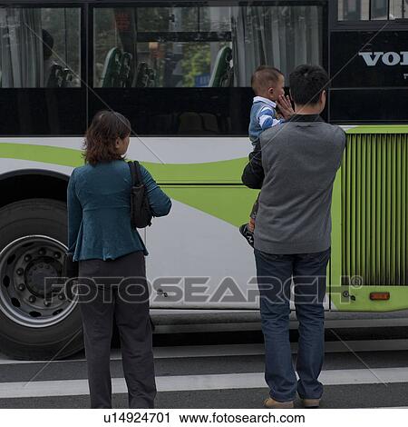 Stock Image - Family standing on the road with bus in the background, Shanghai, China. Fotosearch