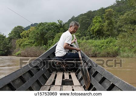 Stock Photo - Man rowing a boat in the river, Thailand. Fotosearch