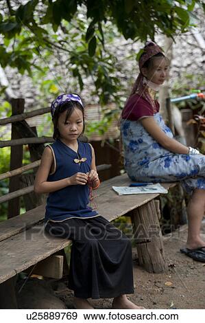 Stock Photo - Padaung girl and a woman sitting on a bench, Huay Pu Keng, Mae Hong Son Province, Thailand. Fotosearch