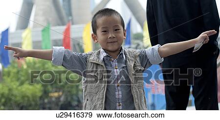 Stock Photo - Portrait of a boy smiling with arms outstretched, Shanghai, China. Fotosearch