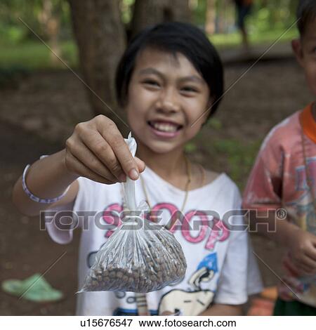 Stock Photo - Portrait of a girl holding a plastic bag of seeds, Thailand. Fotosearch