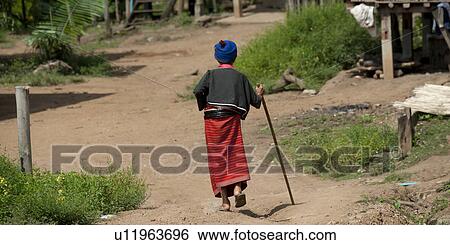 Stock Photograph - Rear view of a person walking with a stick, Chiang Dao, Chiang Mai Province, Thailand. Fotosearch