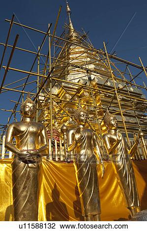 Stock Image - Statues of Buddha in front of a pagoda under renovation at Wat Phrathat Doi Suthep, Chiang Mai, Thailand. Fotosearch