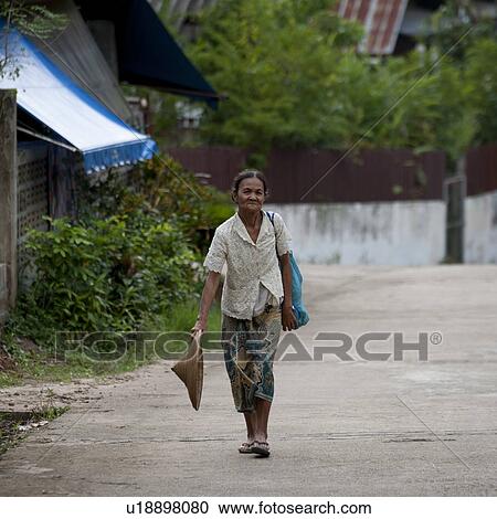 Stock Image - Thai woman walking on a street, Thailand. Fotosearch