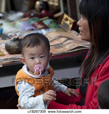 Stock Photo - Woman carrying her son, Shanghai, China. Fotosearch