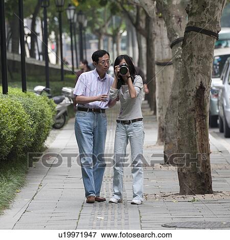 Woman taking a picture with her husband, Shanghai, China View Large Photo Image Stock Photo - Woman taking a picture with her husband, Shanghai, China. Fotosearch
