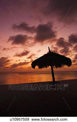 Stock Photo - Aruba, silhouette of palapa on beach at sunset. Fotosearch