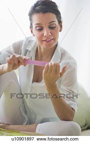 Attractive young woman filing nails View Large Photo Image Stock Photo - Attractive young woman filing nails. Fotosearch