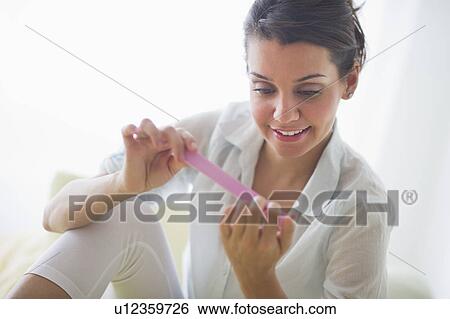 Attractive young woman filing nails View Large Photo Image Stock Photograph - Attractive young woman filing nails. Fotosearch