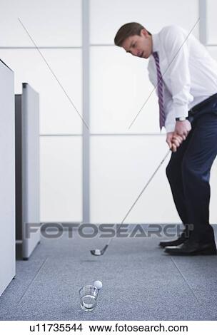 Businessman playing golf at office View Large Photo Image Picture - Businessman playing golf at office. Fotosearch