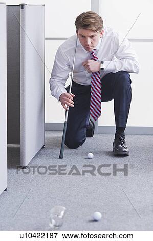 Stock Photo - Businessman playing golf at office. Fotosearch