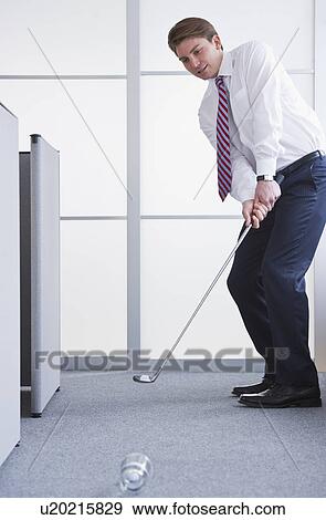 Businessman playing golf at office View Large Photo Image Stock Photo - Businessman playing golf at office. Fotosearch