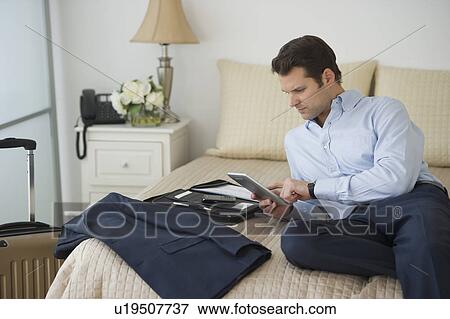 Stock Photo - Businessman using digital tablet in hotel room. Fotosearch