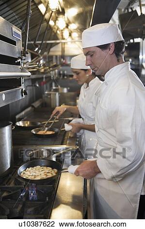 Chef and cook preparing food in commercial kitchen View Large Photo Image Stock Image - Chef and cook preparing food in commercial kitchen. Fotosearch