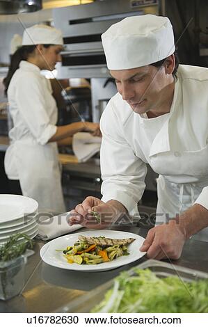 Chef and cook preparing food in commercial kitchen View Large Photo Image Stock Image - Chef and cook preparing food in commercial kitchen. Fotosearch