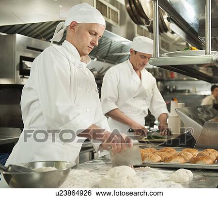 Stock Photograph - Chef cutting pastry to make rolls. Fotosearch