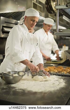Stock Photography - Chef cutting pastry to make rolls. Fotosearch