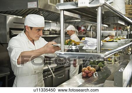 Stock Image - Chefs preparing food in kitchen. Fotosearch
