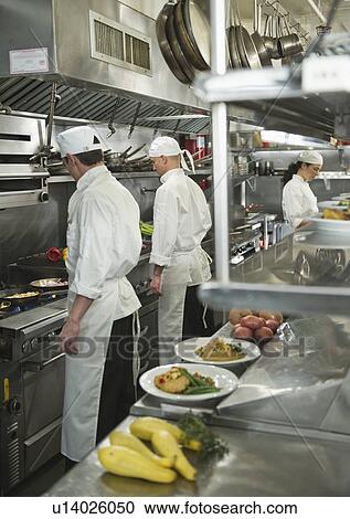 Stock Image - Chefs preparing food in kitchen. Fotosearch
