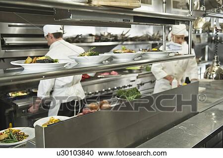 Stock Image - Chefs preparing food in kitchen. Fotosearch