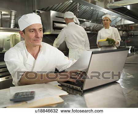 Chefs preparing food, one working on laptop View Large Photo Image Stock Image - Chefs preparing food, one working on laptop. Fotosearch