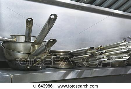 Stock Image - Close up frying pans on shelf in commercial kitchen. Fotosearch