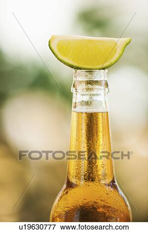 Stock Photo - Close up of bottle of beer with lime slice on top. Fotosearch