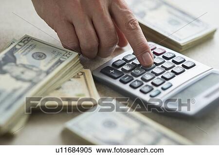 Close-up of man's hand using calculator and stacks of dollar bills View Large Photo Image Stock Photography - Close-up of man's hand using calculator and stacks of dollar bills. Fotosearch