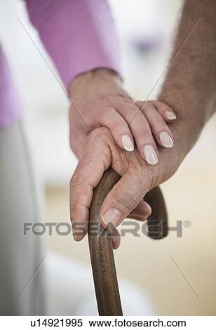 Stock Photography - Close-up of senior couple hands on cane. Fotosearch