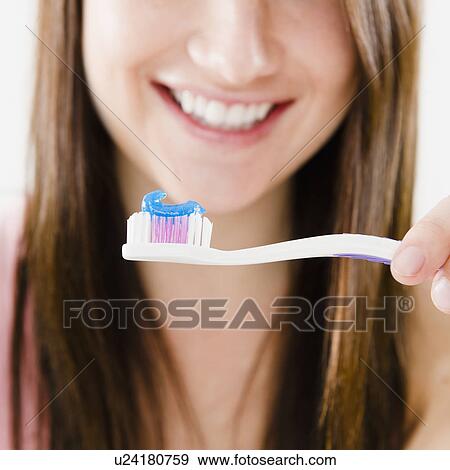 Close-up of smiling young woman holding toothbrush View Large Photo Image Stock Photo - Close-up of smiling young woman holding toothbrush. Fotosearch