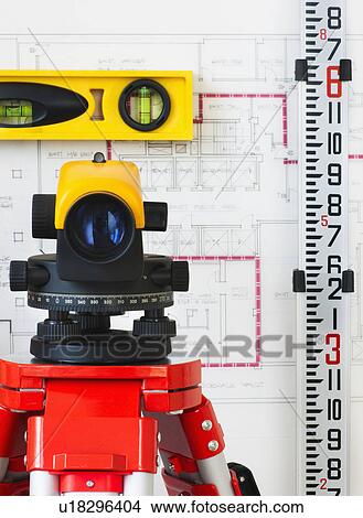 Picture - Close-up of theodolite, blueprint in the background. Fotosearch