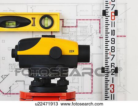 Stock Image - Close-up of theodolite, blueprint in the background. Fotosearch