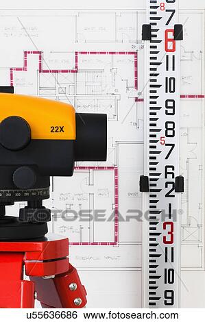 Stock Photograph - Close-up of theodolite, blueprint in the background. Fotosearch