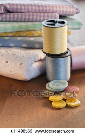 Stock Image - Close-up of thread, buttons and folded textiles. Fotosearch