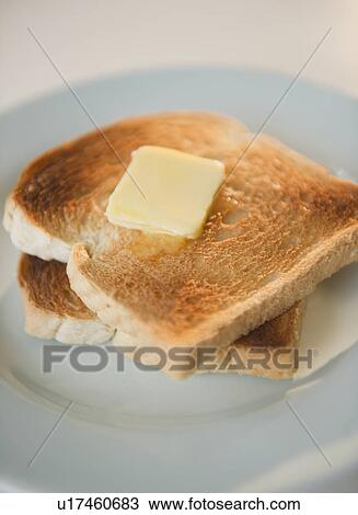Stock Image - Close up of toasts with butter on plate. Fotosearch