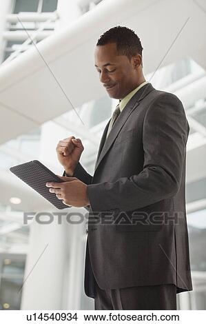 Picture - Content young businessman examining file. Fotosearch