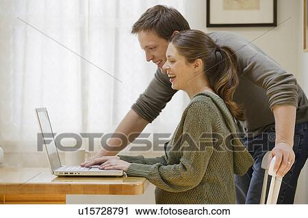 Stock Image - Couple using laptop at home. Fotosearch